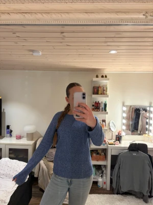 Blå stickad tröja med rund hals - Mysig blå stickad tröja med rund hals och långa ärmar. Tröjan har en enkel och stilren design, perfekt att matcha med jeans eller kjol. Materialet ser ut att vara mjukt och bekvämt, vilket gör den skön att bära under kyligare dagar.