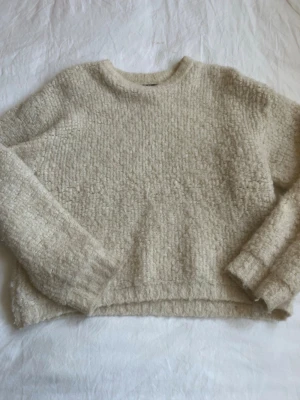 Beige stickad tröja Gina Tricot - Mysig beige stickad tröja från Gina Tricot i storlek XS. Tröjan har en rund halsringning, lång ärm och en fluffig, strukturerad yta som ger en avslappnad look. Perfekt för lager på lager under kyliga dagar.