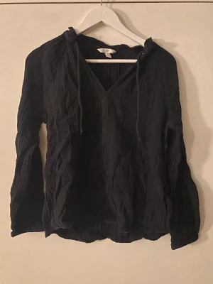 Svart blus  - Långärmad modell med avslappnad passform och v-ringning. Perfekt för en chill och stilren look.