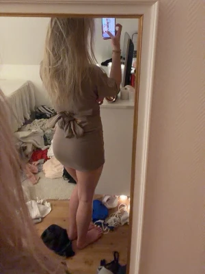 Beige kort klänning med rosett från Gina  - Säljer en beige kortklänning med stor rosett i ryggen och korta ärmar. Klänningen har en figurnära passform och är perfekt för dig som gillar en enkel men söt stil. Materialet känns mjukt och stretchigt.