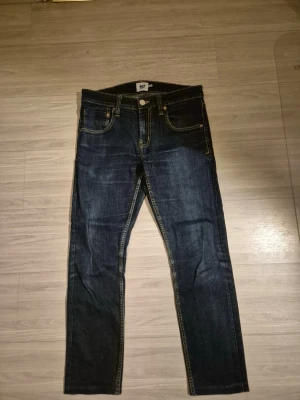 Mörkblå jeans från 157 - Snygga mörkblå jeans från 157 med klassisk femficksdesign och kontrastsömmar. Jeansen har rak passform och är tillverkade i slitstarkt denimtyg. Perfekta för en avslappnad och trendig look. Storleken är M men skulle säga att den passar w30 L28
