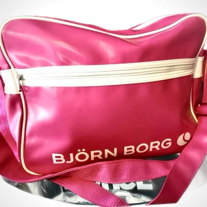 Stor crossover bag från Björn Borg!  - Stor ceriserosa crossover bag med ett stort fack och flera mindre både invändigt & på framsidan samt rejäl justerbar axelrem. Mått: 35 x 30 cm. Väskan är i mycket fint skick!