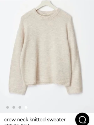 Beige stickad tröja  - Mysig beige stickad tröja med rund halsringning och långa ärmar. Tröjan har en avslappnad passform och ribbade muddar vid ärmslut och nederkant. Perfekt att slänga på sig till jeans eller kjol för en enkel och stilren look.