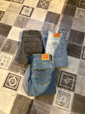 Levi's 3 pack jeans - Tre par Levi's 551z jeans i olika färger: ett par svarta, ett par ljusblå och ett par klassiskt blå. Alla är Levi’s 551z size 16. Dom är 38cm,38cm och 40cm i midja och alla 101cm långa.