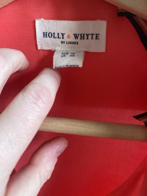 Korallröd skjorta Holly & Whyte - Säljer en snygg korallröd skjorta från Holly & Whyte by Lindex. Skjortan har klassisk krage, långa ärmar och knappar framtill. Tillverkad i ett mjukt och lätt material som känns skönt mot huden. Perfekt för dig som vill ha en färgklick i garderoben!