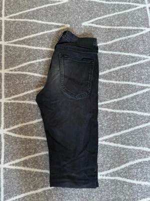 Mörkgråa Lee jeans med rak passform - Säljer ett par mörkgråa jeans från Lee med klassisk rak passform. Jeansen har fem fickor, Lee-logga på bakfickan och svart patch i midjan. Materialet är denim i bomull med en snygg tvättad look. Perfekta till en avslappnad stil. Storlek W27 L32. Hör av er vid frågor eller lägg ett prisförslag!