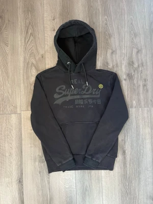 Svart hoodie från Superdry - Svart hoodie från Superdry med stor logga och japansk text på bröstet🤩 Passar både M-S inga fel🙌🏻 hör av er vid funderingar samt snabbaffär😇