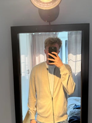 Beige ziptröja i bomull från Massimo Dutti - Snygg beige ziptröja med dragkedja framtill! Tröjan är näst intill nyskick. Moddellen är 185cm och väger 74 kg.