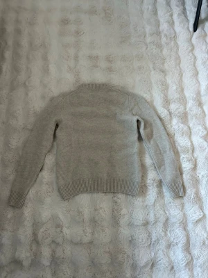 Beige stickad tröja från Bläck - Säljer en stilren beige stickad tröja från Bläck. Tröjan har rund halsringning, långa ärmar och ribbade muddar vid ärmslut och nederkant. Perfekt för lager på lager och enkel att matcha med olika outfits. Obs, liten i storleken. Nypris 840