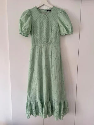 Mintgrön klänning  - Mintgrön långklänning med puffiga kortärmar och vacker broderad spets. Klänningen har rund halsringning, volangkant nedtill och dragkedja i ryggen. Mycket bra skick, endast använd en gång. 