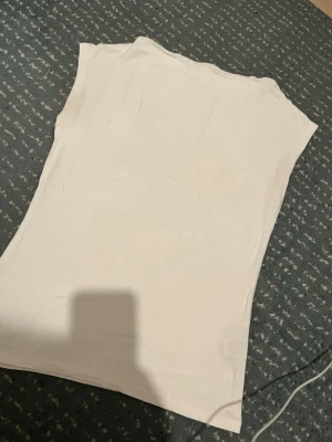 Vit ärmlös topp i bomull - En enkel och stilren vit topp  med ärmlös design. Toppen har rak passform och är tillverkad i ett mjukt material som känns skönt mot huden. Perfekt att matcha med jeans eller kjol för en clean look.