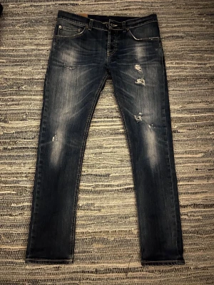 Dondup - Säljer ett par mörkblå skinny jeans med slitningar och distressed detaljer på framsidan. Jeansen har klassisk femficksdesign, kontrastsömmar och en cool tvättad look. Perfekta för en avslappnad streetstyle.