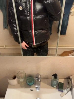 Svart dunjacka från Moncler - Säljer en svart, glansig dunjacka från Moncler med klassisk logotyp på bröstet. Jackan har två sidofickor med dragkedja och en rödvit rand längs dragkedjan framtill. Perfekt för kalla vinterdagar och riktigt snygg streetstil. Köptes utav min polare för 12500 och kan tänka mig gå ner i pris verifiering om att den e äkta visar jag privat. 