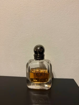 Emporio Armani Stronger With You - Emporio Armani Stronger With You är en elegant parfym i en genomskinlig glasflaska med rundade former och en silverfärgad metallkork. Doften har en varm bärnstensfärgad vätska och flaskan har stilren svart text på framsidan.