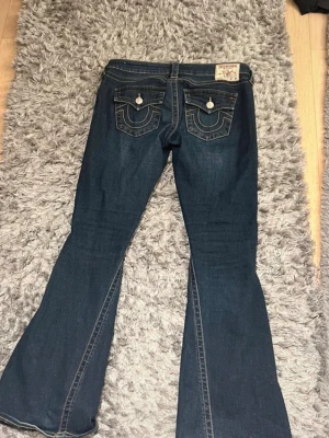 Mörkblå bootcut jeans True Religion - Säljer ett par mörkblå bootcut jeans från True Religion , detaljer på fickorna och i storlek 28. Lite trasiga längst ner (se bild). Köpte på Vinted men var tyvärr för stora, lånade bilder. Kom gärna med prisförslag och skriv om ni har frågor💕