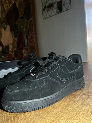 Nike Air Force 1 Low black cat helsvart mocka - Säljer ett par nya nike airforce 1 black cat limited edition då dom ej passar mig och är en storlek för stora. Storlek 45 använt en gång endast. Orginal låda finns med. Nike airforce 1 07 lv7 