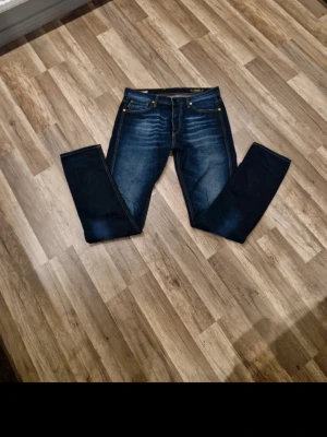 Jack and Jones - Snygga mörkblå raka jeans med slitningar och kontrastsömmar. Klassisk femficksmodell och normal midja. Jeansen har en cool tvättad look och passar perfekt till en avslappnad stil. Materialet är troligtvis bomull med lite stretch för extra komfort.