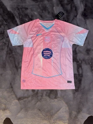 Barça rosa matchtröja Nike - Snygg rosa och ljusblå FC Barcelona matchtröja från Nike med klubbmärke och Spotify-logga på bröstet. Den är storlek L men sitter mer som M. Tröjan har korta ärmar, V-ringning och är tillverkad i ett lätt, ventilerande material som passar perfekt till träning eller match.