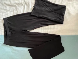 Svarta basic joggapants  - Ett par svarta joggapants med enkel design och stretchigt material. De har en bred resår i midjan och utsvängda ben. Perfekta att matcha med oversized tröjor eller hoodies. Materialet känns mjukt och följsamt.