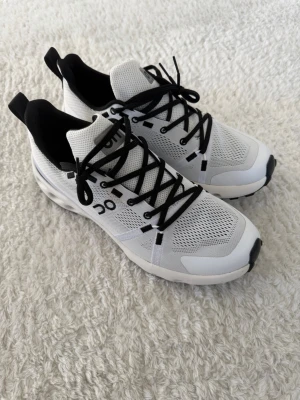 Helt nya vita On cloud sneakers med svart detalj - Helt nya! Snygga vita sneakers från On cloud med svarta detaljer och svarta skosnören. Ovandelen är i mesh för bra ventilation och sulan har On's karakteristiska dämpning. Perfekta för dig som gillar sportig och modern stil.