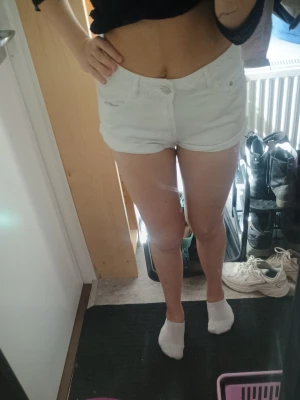 Vita högmidjade jeansshorts - Snygga vita högmidjade shorts i jeansmaterial med råa kanter och klassiska fickor både fram och bak. Perfekta för varma dagar och ger en fräsch look till din outfit.