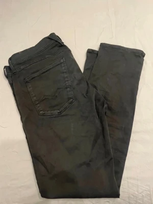 Svarta slim fit Replay jeans  - Säljer ett par svarta slim fit jeans med klassisk femficksdesign och normal midja. Jeansen har raka ben och är tillverkade i ett mjukt bomullsmaterial med lite stretch för extra komfort. Perfekta för en clean och stilren look.