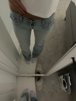 Ljusblå low waist bootcut jeans - Säljer ett par så fina ljusblå low waist jeans med bootcut-modell. Jeansen har två framfickor med knappdetaljer. Perfekta för både vardag och fest. Så så så snygga💓