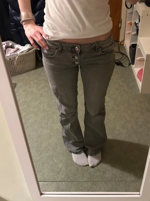 Grå lågmidjade jeans - Säljer ett par ljusblå bootcut jeans med låg midja. Jeansen har en grå tvätt och är tillverkade i denim med lite stretch för skön passform samt justerbar resår i midjan. Jag är 168cm lång💕INNERBENSLÄNGD : 77cm