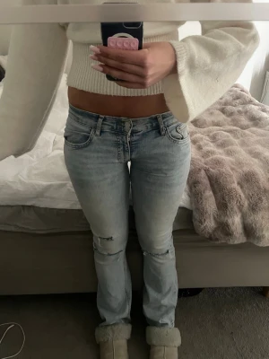 Ljusblå bootcut jeans med hål - Säljer ett par ljusblå bootcut jeans hål vid knäna. Jeansen är lite nedsydda.🩷