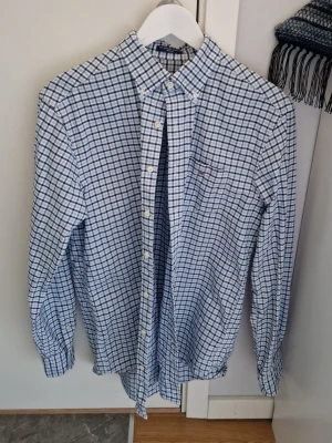 Blårutig skjorta från Gant - Säljer en klassisk blårutig skjorta från Gant i storlek M. Skjortan har button-down krage, bröstficka och vita knappar. Tillverkad i mjuk bomull och har regular fit. Perfekt för en clean och stilren look.