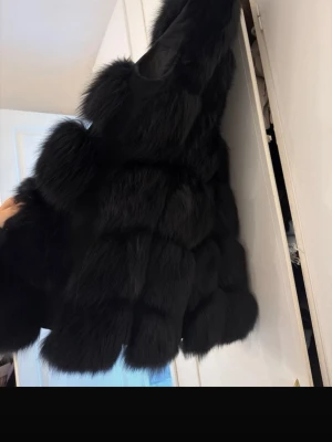 Svart fluffig pälsväst - Säljer en superfluffig svart pälsväst med stora, mjuka pälspartier och quiltat innerfoder. Västen har en lyxig look och är perfekt för dig som vill sticka ut. Ingen synlig logga eller märke. Passar till lager på lager och ger en trendig vibe.