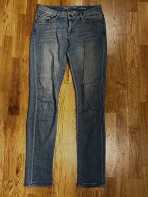 Ljusblå Jeans från Sisters - Storlek: W27/L33 - Ljusblå jeans från Sisters säljes! Snygga och bekväma jeans i klassisk design med två framfickor och två bakfickor. Knäpps med knapp och dragkedja. Storlek: W27/L33. Material: 98% Bomull, 2% Elastan. Säljs i begagnat skick, mindre skada finns (se sista bilden för detaljer!) Modell: Ebba. Djur- och rökfritt hem! Kika gärna in mina andra annonser!