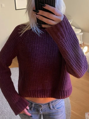 Vinröd chunky stickad tröja - Mysig vinröd stickad tröja med grov struktur och ribbade muddar vid ärmslut och nederkant. Tröjan har en avslappnad passform och högre rund halsringning. Perfekt för lager på lager och höstiga outfits.