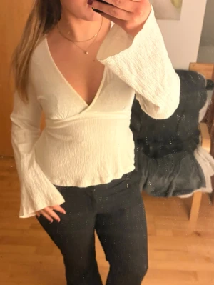 Vit wrap top / omlottopp – Gina Tricot - Jättefin vit omlottopp från Gina Tricot 🤍 Flödigt tyg, långa utsvängda ärmar och supersnygg passform. Ger en clean men ändå chic look – perfekt för brunch, skola eller utekväll.  Storlek M, sitter väldigt fint!  I mycket bra skick ✨