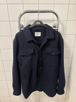 Mörkblå overshirt från These Glory Days - Stilren mörkblå overshirt från These Glory Days. Använd 1 gång.