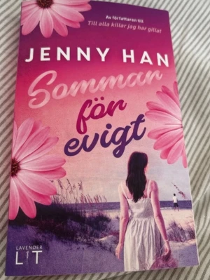Sommar för evigt av Jenny Han - En färgstark pocketbok med omslag i rosa och lila toner, dekorerad med stora blommor och en strandscen. Boken är skriven av Jenny Han och heter 'Sommar för evigt'. Perfekt för dig som gillar romantisk ungdomslitteratur.
