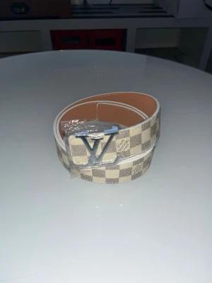 Bälte - Beige med grå rutor samt silver märke bälte