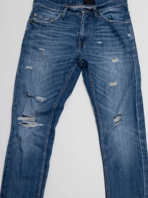 Tiger of sweden jeans  - Säljer ett par blå jeans från Tiger of Sweden med slitningar och hål på flera ställen framtill. Jeansen har klassisk femficksmodell och normal passform. Perfekta för en avslappnad och trendig look.