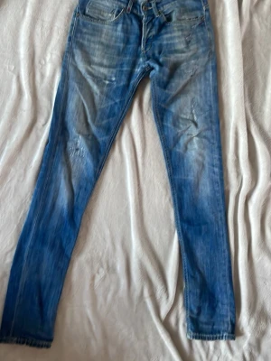 Dondup Jeans modell George  - Säljer ett par blå jeans från Dondup med smal passform och slitna detaljer på benen. Modell George. Stlk 31. Skick 5/10. Skicka dm vid frågor. Postar alltid snabbt ⭐️