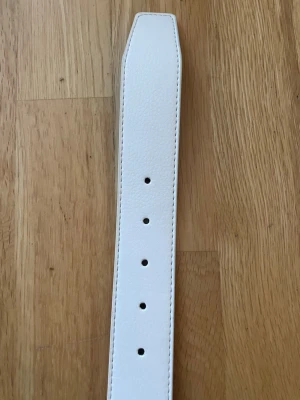 Vitt brett bälte i skinnimitation - Vitt bälte som är i skin det är 120cm långt och är aldrig använt 