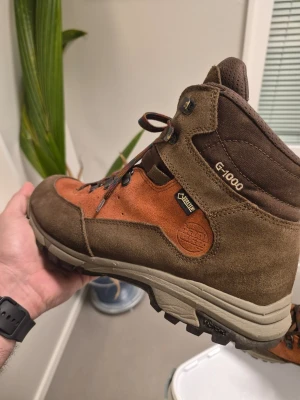 Hanwag Tudela Light Lady GTX G-1000, Brun/orange EUR 42 - Tudela Light Lady GTX från Hanwag är en exceptionellt lätt och bekväm känga för enklare vandringar och långa promenader. – Gezwickte style, så Wiederbesatt – Långvarigt, vattentätt och andningsbart GORE-TEX-foder – Rak passform – Ribbor – mer plats för tårna och rak stortå – Vibram-sula – Superlätt – endast 505g – snörning tack vare flexibel infästning på remmar – Flexzoner på skons framsida – Klämkrokar för snabb och precis remmar – Lätt Tillverkad av en blandning av sportmocka och G-1000 Heavy