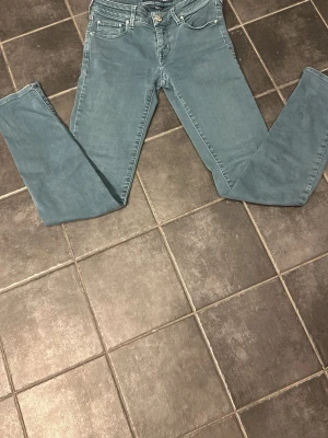 Blå slim fit jeans från Jacob cohen - Snygga blå slim fit jeans från Jacob cohen med klassisk femficksdesign och normalhög midja. Jeansen har raka ben och är tillverkade i ett mjukt denimtyg med lite stretch för extra komfort. Perfekta till en avslappnad stil.