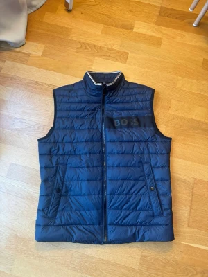 Boss väst - Jag En helt oanvänd väst jag spontan köpte och inte alls har använt. Jätte fin mörkblå färg och helt oanvändbar. Jag är 185 och har M och västen passar M/L