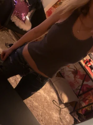 Mörkgrå ribbad linnetopp - Snygg mörkgrå ribbad linnetopp med smala axelband och rundad halsringning. Toppen är croppad och sitter tight, perfekt att matcha med jeans eller kjol. Enkel och stilren design som passar till många olika looks.