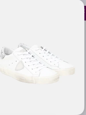 Vita Philippe Model sneakers med leopard - Snygga vita sneakers från Philippe Model med silverfärgade leoparddetaljer på hälen och klassisk snörning. Skorna har en ikonisk sköld på sidan och är tillverkade i skinn med syntetdetaljer. Perfekta för dig som gillar en clean look med lite edge.