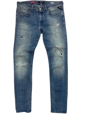 Blå slitna jeans från Replay - Säljer ett par blå jeans från Replay med snygga slitningar och distressed detaljer. Jeansen har fem fickor, normal midja och raka ben. Materialet är klassisk denim med en cool tvätt som ger en avslappnad vibe.