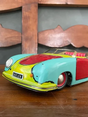 Distler plåtleksaksbil retro - Säljer en färgglad retro plåtleksaksbil från Distler. Bilen är turkos med röda och gula detaljer, har öppet tak och klassisk sportbilsdesign. Snygga röda säten och detaljerad front med Distler-märke. Perfekt för samlare eller som cool inredningsdetalj. Bilen saknar ett däck och är i ganska dåligt skick. Den är även ommålad. 