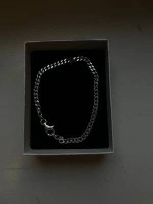 Silverfärgat kedjearmband - Stilrent armband i silverfärg med platt kedjedesign och karbinlås. Perfekt accessoar för att lyfta din outfit med en clean och modern look. Passar både till layering och att bära ensam för en minimalistisk vibe.