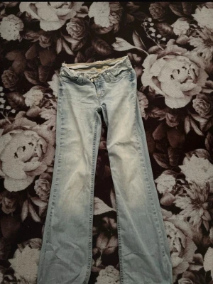 Ljusblå bootcut jeans - Säljer ett par ljusblå bootcut jeans med klassisk femficksdesign och rå kant i midjan. Jeansen har en avslappnad passform och är tillverkade i mjukt denimtyg. Perfekta för en casual look och lätta att matcha med olika stilar. Pris kan diskuteras bilder &info kom privat för det!!