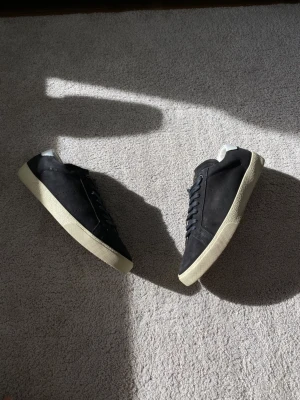 Saint Laurent Court Classics Mocka - Snygga sneakers från Saint Laurent med klassisk låg profil och vit sula. Skorna har svarta skosnören och diskret logga i guld på plösen. Perfekta för en clean och stilren look.